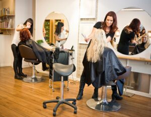 Hairdresser styling a client's long blonde hair in a modern salon.